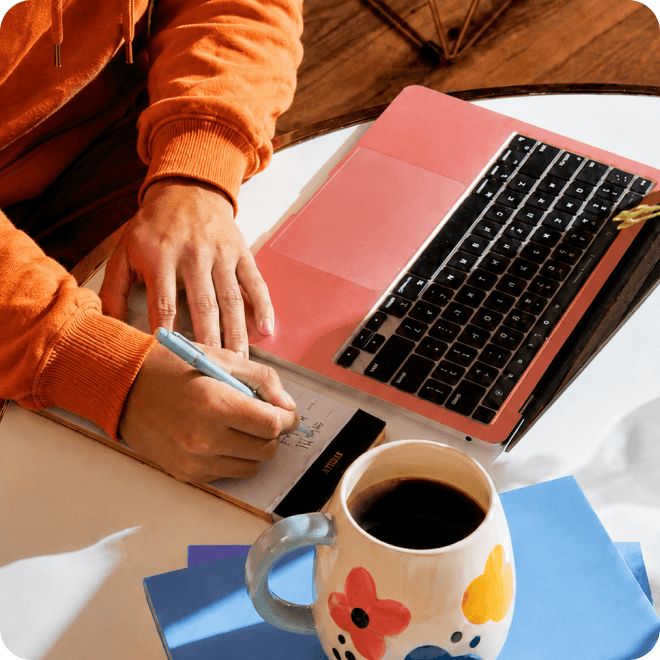 Hands typing on a laptop next to a mug of coffee